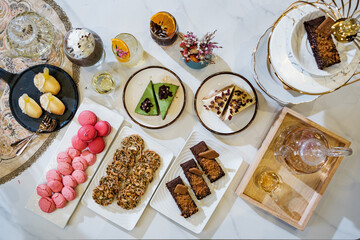 A variety of French pastries, arranged on serving plates, are prepared for sale in a pastry shop.