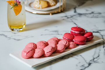 Colorful vivid pink macarons serving on white dish beside of freshness herbal tea at the afternoon