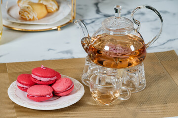 Colorful vivid pink macarons serving on white dish beside of freshness herbal tea at the afternoon