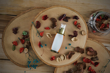 Top view still life pack shot photograph of aromatic spray bottle put on wooden log surround by scented dried flowers