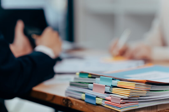 Organization's paper: The image captures a detailed view of a stack of documents organized on a desk. The scene offers a glimpse into a workplace environment focused on administration.