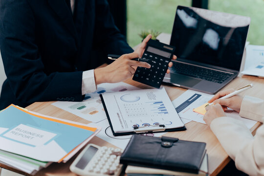 Analyzing Financial Data: An overhead shot showcases a business professional meticulously analyzing financial data, utilizing a calculator and laptop, while taking notes on a notepad.