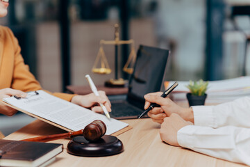 Legal Consultation: Two professionals sit at a desk, carefully reviewing and signing legal...