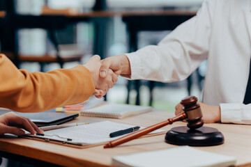 Handshake Deal: A close-up shot of two individuals sealed an agreement with a firm handshake, with a gavel on desk symbolizing legal authority, conveying a sense of finality and closure.