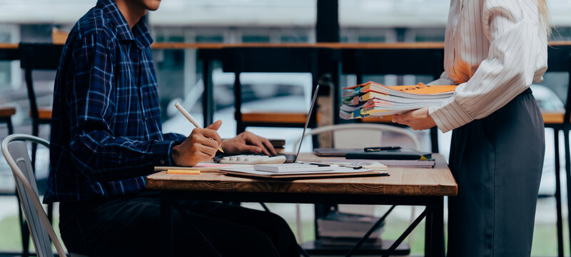 Collaborative Office Dynamics: Two individuals engage in a dynamic exchange of ideas and documents, their workspace fostering a synergy of shared objectives, creativity, and focused work. 