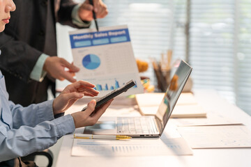 Analyzing Business Metrics: A focused professional meticulously reviews financial reports alongside a colleague.