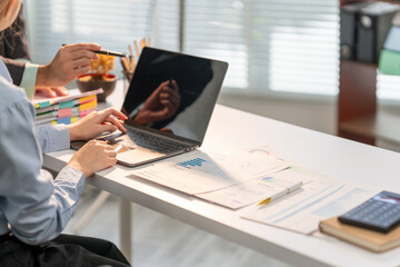 Business professionals at Work: An intimate glimpse into the world of business as professionals collaborate over a laptop, documents, and calculations, showcasing a commitment to their tasks. 
