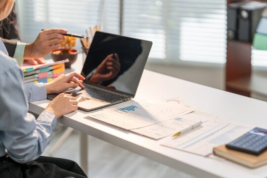 Business professionals at Work: An intimate glimpse into the world of business as professionals collaborate over a laptop, documents, and calculations, showcasing a commitment to their tasks. 