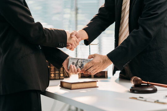 Deal Handshake & Bribery : A decisive handshake seals an under-the-table financial transaction. Two figures exchange a bundle of money, with the gavel in the corner hinting at the law. - Powered by Adobe