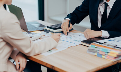 Analyzing Business Strategy: Two professionals analyze data, charts, and graphs during a meeting. The focus is on the intricacies of strategy, decisions, and business processes