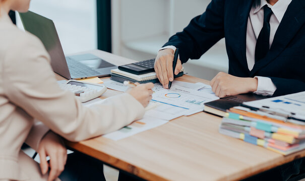 Analyzing Business Strategy: Two professionals analyze data, charts, and graphs during a meeting. The focus is on the intricacies of strategy, decisions, and business processes