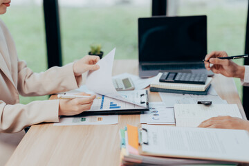 Analyzing Collaboration: Close-up of two individuals engrossed in an in-depth financial analysis within a modern office setting, signifying cooperation and deliberation.