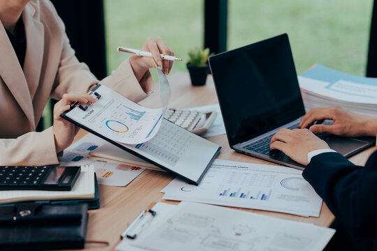 Business Strategy Session: Two professionals in a modern office analyze financial reports and data. The scene captures the essence of strategic planning, financial analysis.