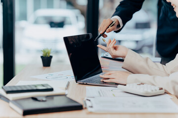 Business Collaboration: Close-up shot of two professional interacting over a laptop, highlighting the dynamics of teamwork.