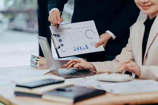 Data Analysis Duo: A close-up shot of two business colleagues collaboratively analyzing charts and reports in a modern workspace.