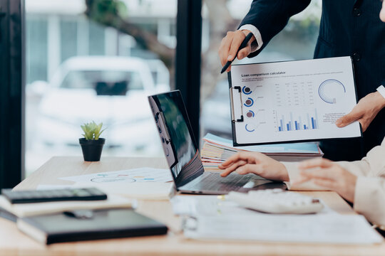 Business Analysis: A focused scene of business colleagues collaborating over a laptop, analyzing financial reports, with a sleek, modern office interior as backdrop.