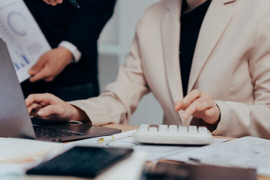 Focused Collaboration: Close-up of hands typing on a laptop and using a calculator, capturing a scene of collaborative work