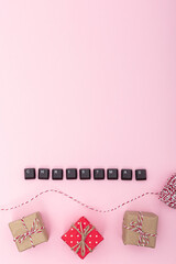Gift box and word christmas made of keyboard keys on pink background. Symbol of digital holiday, online communication and modern festive creativity connection. Vertical photo, copy space