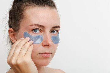 Close up portrait of a young european girl or woman a blue mask and patches for the skin around the eyes. Copy space