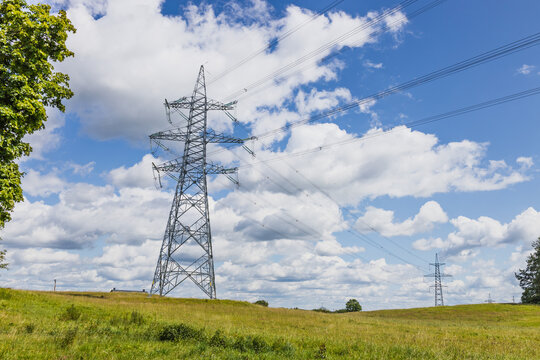 High voltage power lines and steel transmission towers across rural meadow