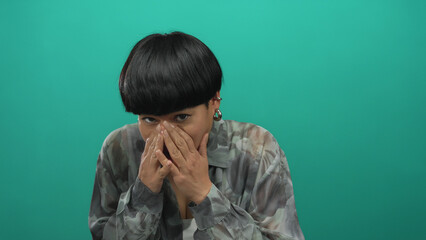 Woman expressing fear over isolated green background in a series of images, highlighting her...