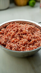 Raw ground meat in a white bowl on kitchen counter. Fresh minced beef or pork with natural texture. Perfect for cooking, recipe, meal preparation, and food photography content.