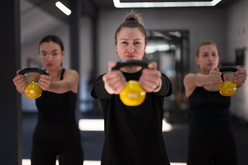 Women exercising with kettlebells in a gym setting during a group workout session for strength training