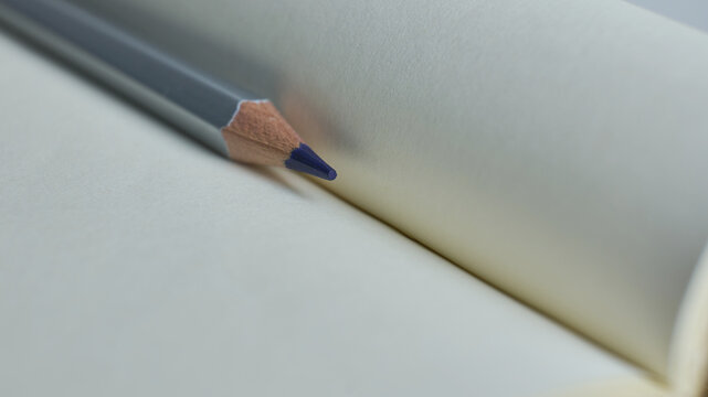 Blue pencil resting on blank notebook pages