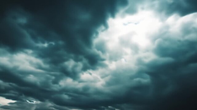 Dramatic storm clouds gathering in a dark sky with a bright ray of light breaking through, foreboding weather.
