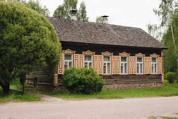 Historic wooden house with decorative trim located on a quiet street surrounded by greenery