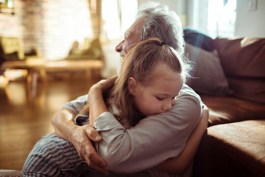 Senior grandfather and child granddaughter share a comforting hug at home