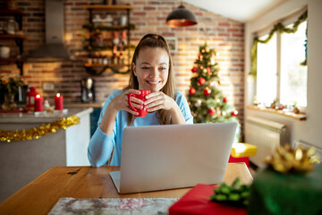 Young adult woman smiling on laptop at home at christmas
