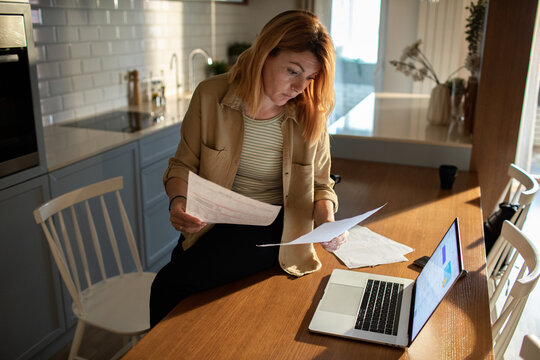Adult woman worried reviewing bills at home kitchen table