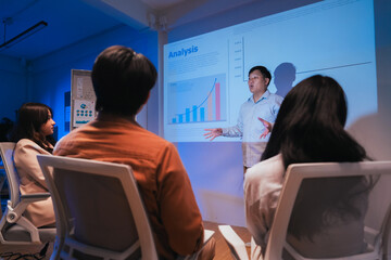young Asian software development manager leads a late-night office discussion with his executive team, mentoring developers and analyzing source code to guide programming and project development	