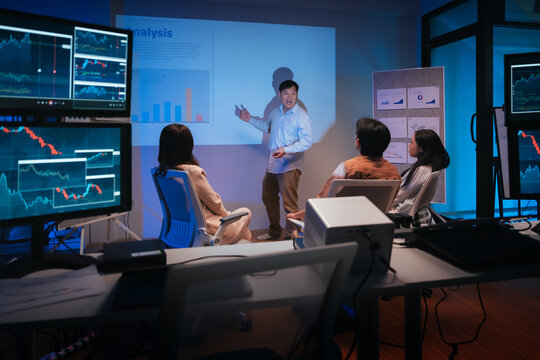 young Asian software development manager leads a late-night office discussion with his executive team, mentoring developers and analyzing source code to guide programming and project development	