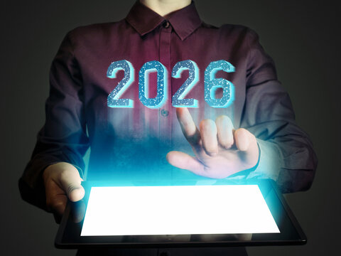 A business woman presses on a glowing holographic 2026 numbers, representing technology, innovation, progress, and upcoming opportunities.
