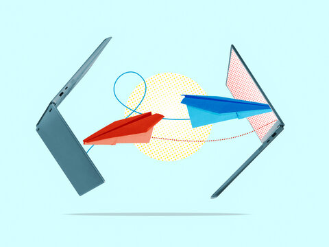 Paper airplanes fly from one laptop to another.