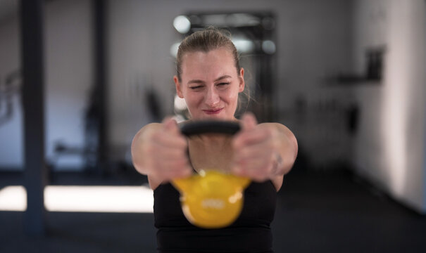 Young woman training with kettlebell in gym focused on fitness and strength building in morning hours