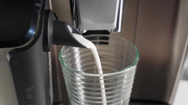 Milk flows smoothly from the frother into a glass. Fresh, hot foam builds for a creamy drink.