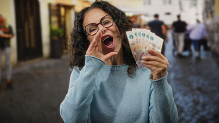 Middle-aged woman joyfully holding argentine pesos outdoors in a bustling city street, expressing...