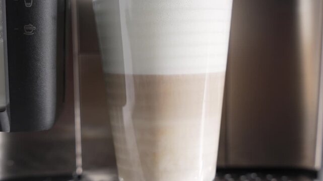 A tall latte macchiato shows clean layers of milk, espresso, and foam. Cafe-style at home.