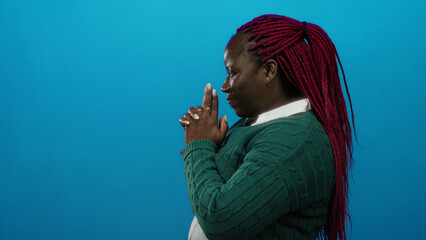 Woman playfully poses with finger gun gesture against a vibrant blue background, expressing...