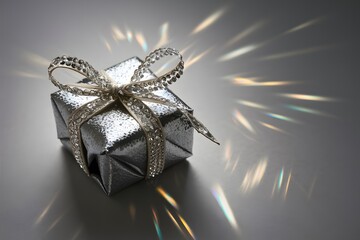 Silver gift box with ribbon on a blurred shine background  