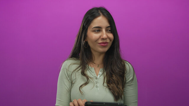 Young hispanic woman using tablet against bright pink background conveying modern technology and digital lifestyle in an isolated and focused setting. - Powered by Adobe