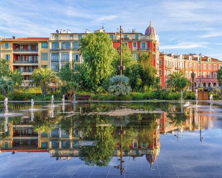 Nice, France. Beautiful reflection of colorful historic buildings and fountains at Promenade du Paillon. A peaceful city park on the French Riviera with palm trees and clear blue sky.
