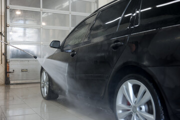 Naklejka premium Washing auto with high pressure water jet at car wash, closeup