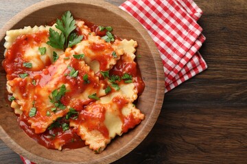 Delicious ravioli with tomato sauce and parsley on wooden table, top view