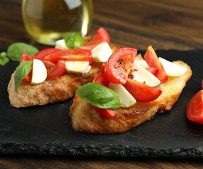 Tasty bruschettas with mozzarella cheese, tomatoes and basil on wooden table, closeup