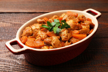 Delicious cooked stew in baking dish on wooden table, closeup