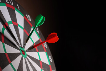 Dartboard with darts on black background, closeup. Space for text